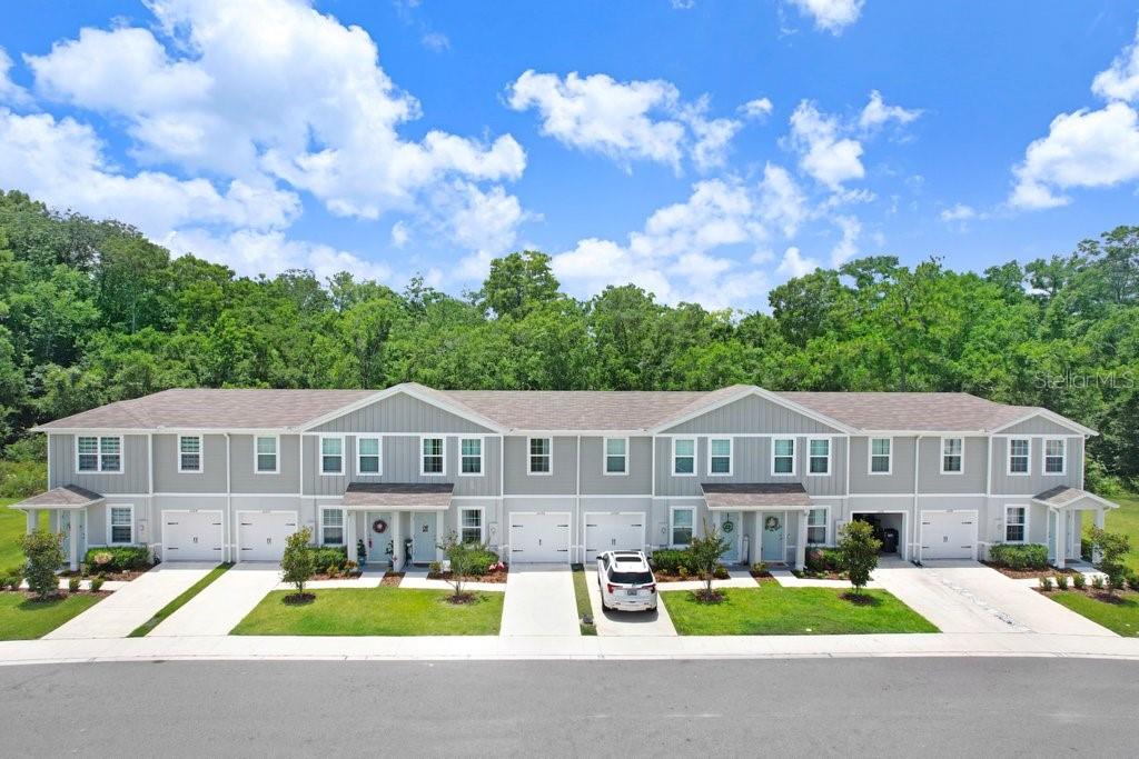 A row of light gray townhomes with attached garages and a shared driveway — 12214 GRIZZLY LANE, NEW PORT RICHEY, FL