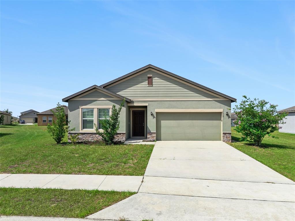 A single-story house with green siding, a stone facade, and a two-car garage — 409 STILLWATER LANE, HAINES CITY, FL
