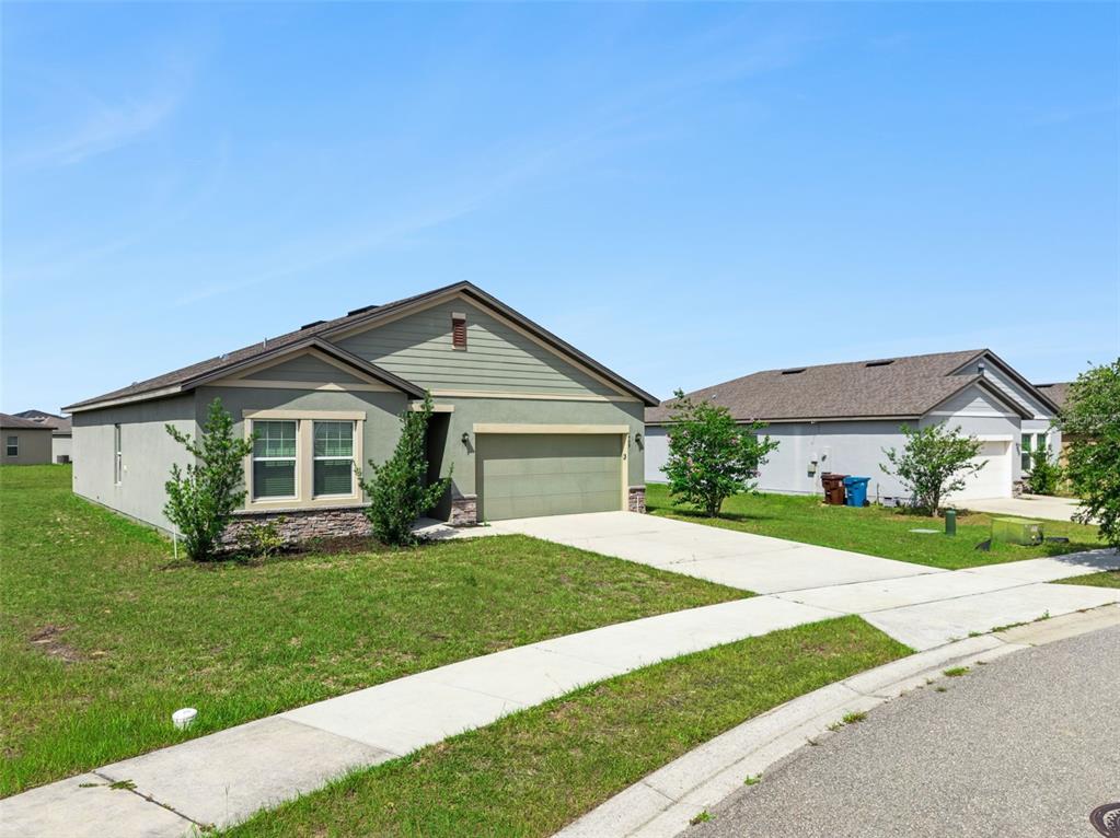 A single-story house with a green exterior, stone accents, and a two-car garage — 409 STILLWATER LANE, HAINES CITY, FL