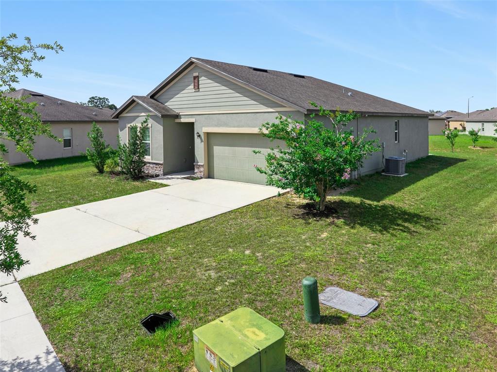 A single-story house with a beige exterior, a two-car garage, and a concrete driveway — 409 STILLWATER LANE, HAINES CITY, FL