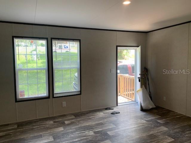 An open living area with wood-look flooring, two windows, and a door leading outside — 10830 LIBBY NUMBER 3 ROAD, CLERMONT, FL