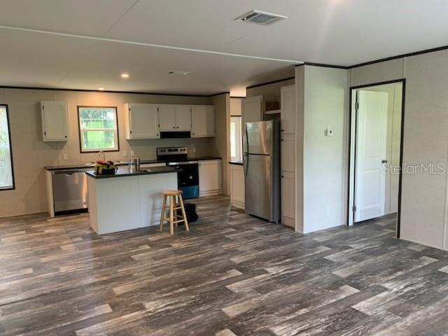 A living room with light-colored walls, wood-look flooring, two windows, and a glass exterior door — 10830 LIBBY NUMBER 3 ROAD, CLERMONT, FL