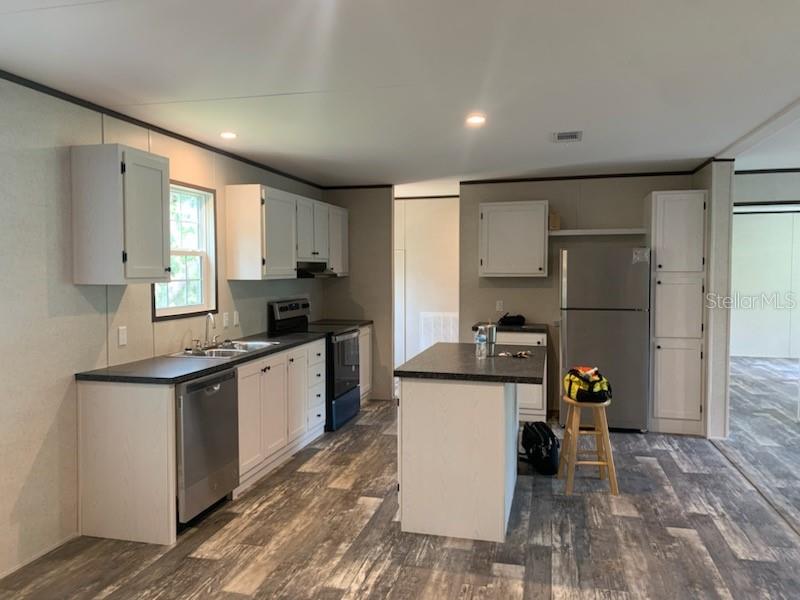 A kitchen with white cabinets, stainless steel appliances, a center island, and wood-look flooring — 10830 LIBBY NUMBER 3 ROAD, CLERMONT, FL