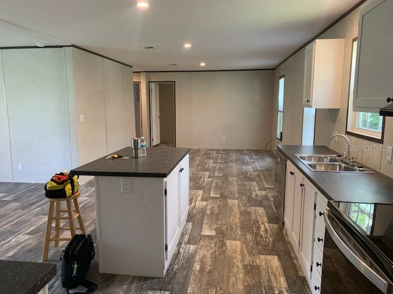 A kitchen with a central island, white cabinets, dark countertops, and wood-look flooring — 10830 LIBBY NUMBER 3 ROAD, CLERMONT, FL
