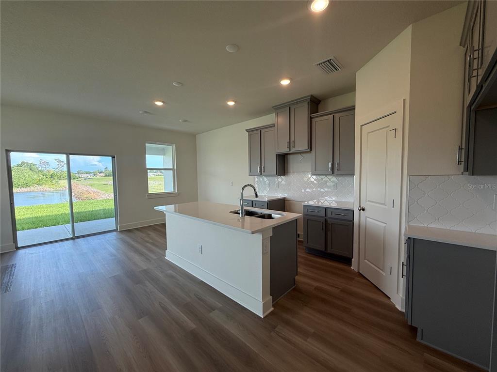 A kitchen with gray cabinets, a white island, and a sliding door overlooking a pond — 13998 EMERALD FIELDS DRIVE Lot 23, HUDSON, FL