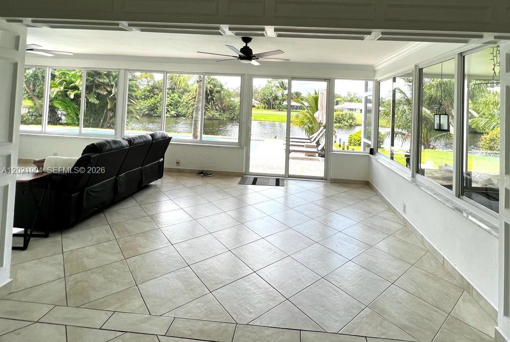 A sunroom features large windows, tile flooring, a ceiling fan, and a view of water — 3324 Lakeview Blvd, Delray Beach FL 33445, DELRAY BEACH, FL