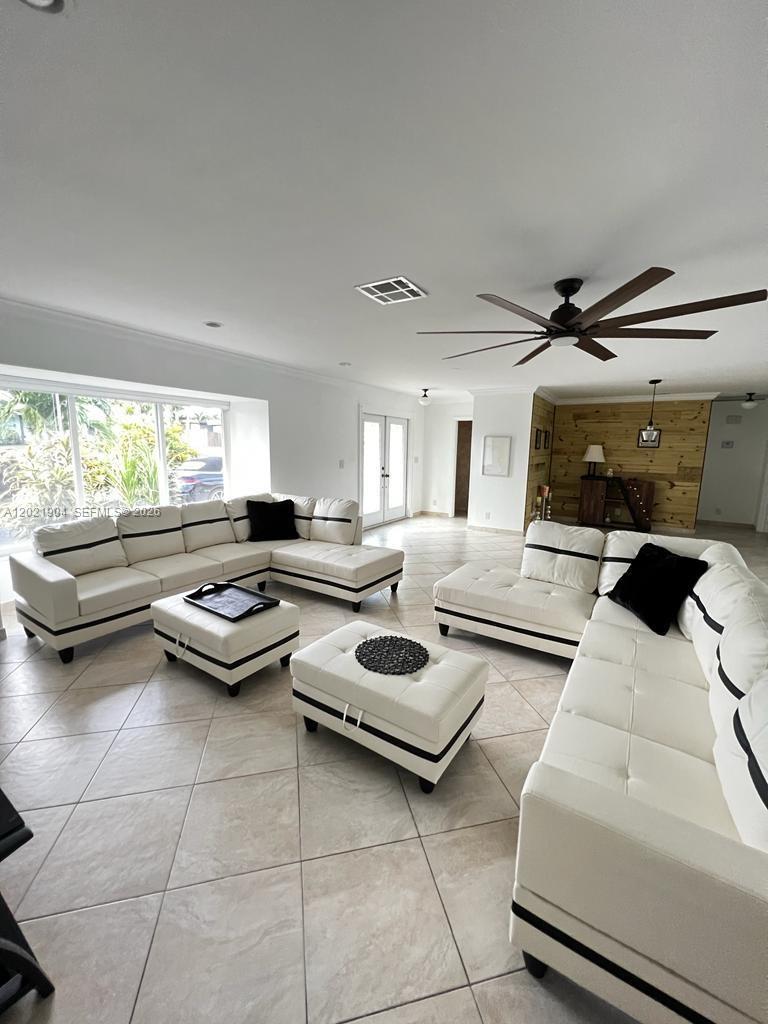 A spacious living room features white sectional sofas, matching ottomans, and a wood-paneled accent wall — 3324 Lakeview Blvd, Delray Beach FL 33445, DELRAY BEACH, FL