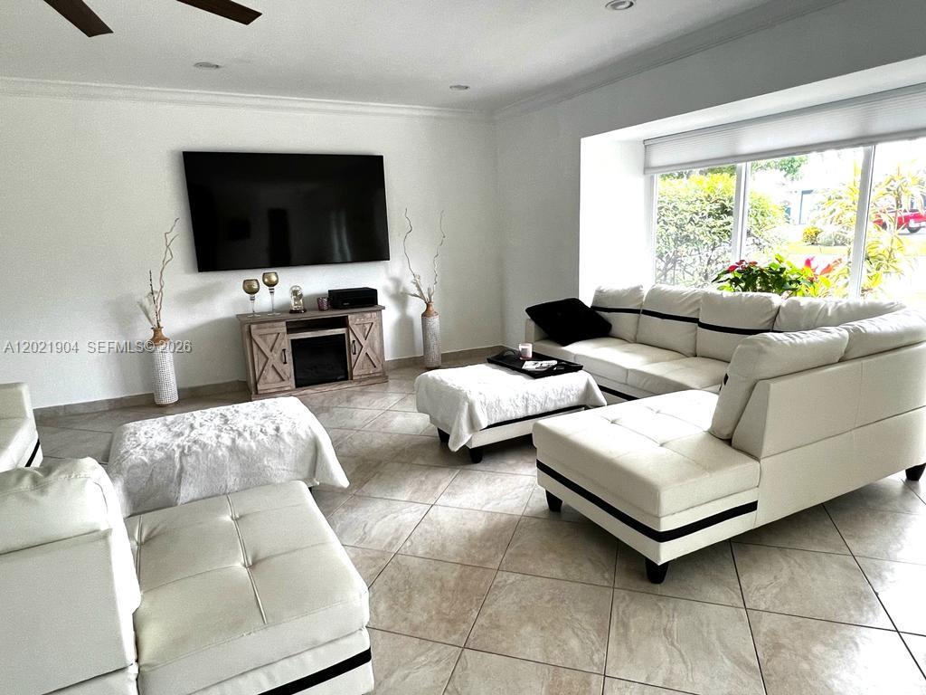 A living room features white sectional sofas, a television, and a fireplace on tiled floors — 3324 Lakeview Blvd, Delray Beach FL 33445, DELRAY BEACH, FL