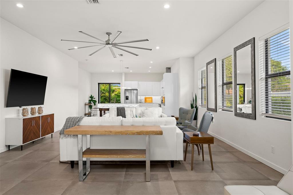 A modern open-concept living room features a white sofa, wood console table, and tile flooring — 5351 MOELLER AVENUE, SARASOTA, FL