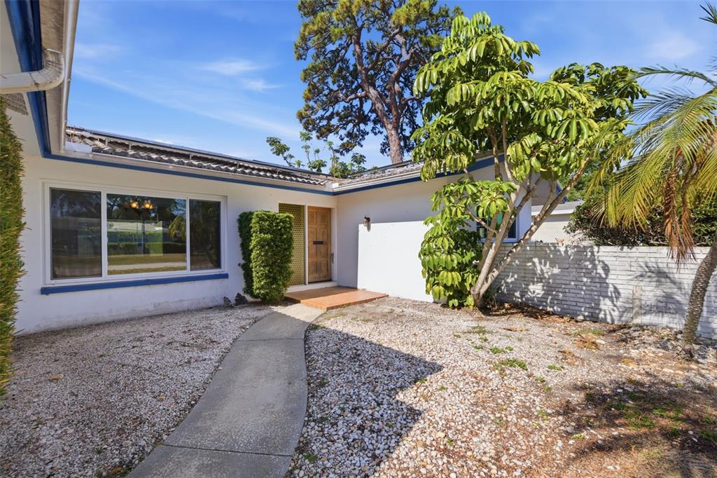 A concrete walkway leads to the front entrance of a white house with blue trim — 1344 62ND PLACE S, ST PETERSBURG, FL