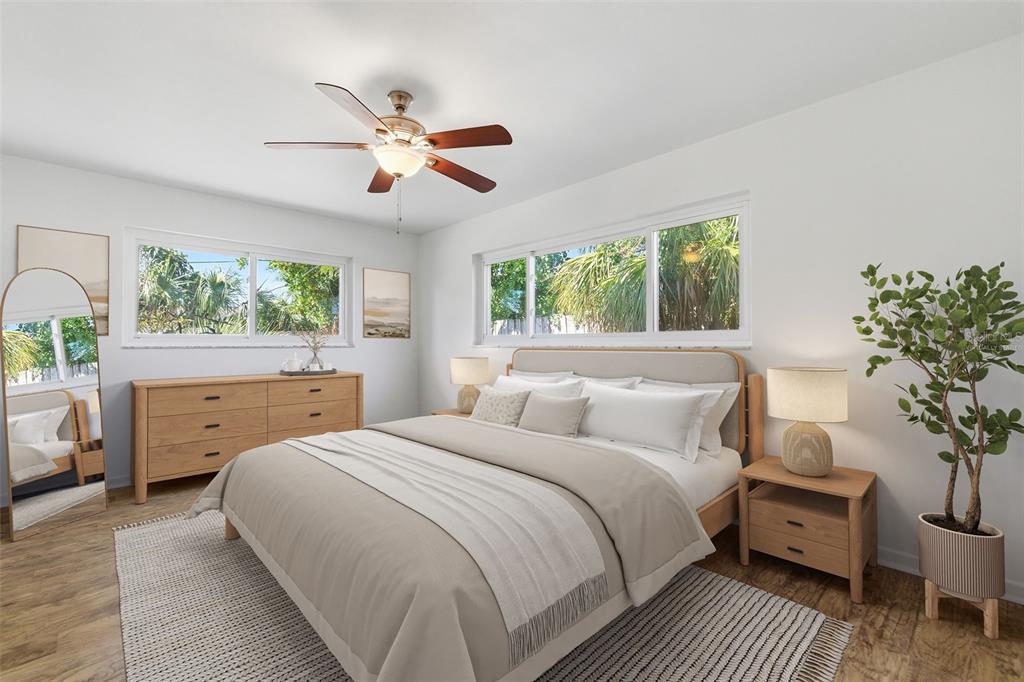 A bedroom features a bed, wooden furniture, a ceiling fan, and large windows with greenery — 1344 62ND PLACE S, ST PETERSBURG, FL