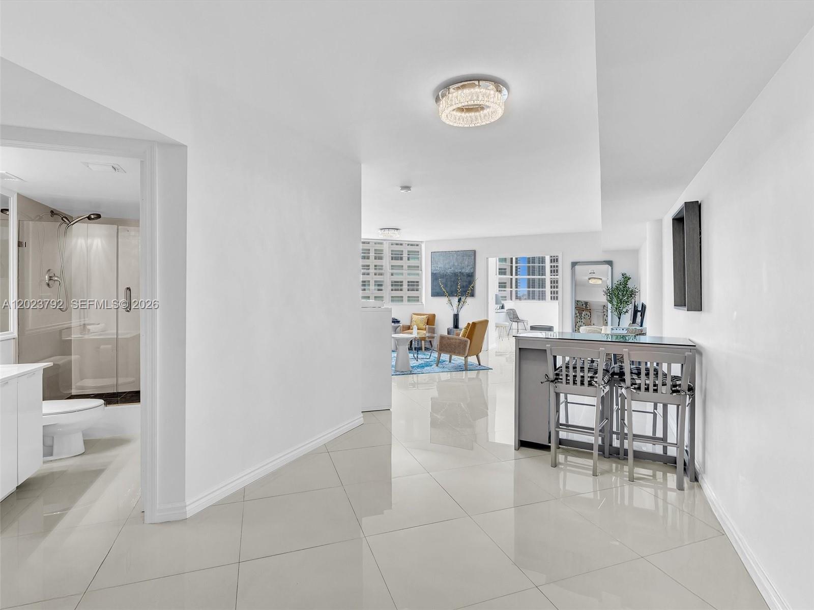 A bright, open-concept interior features white tile flooring, a breakfast bar, and an adjacent bathroom — 825 Brickell Bay Dr # 2048, Miami FL 33131, MIAMI, FL