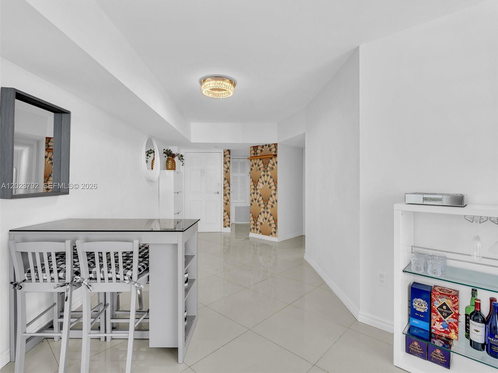 A dining area features a glass-topped table, white chairs, tiled floors, and a decorative accent wall — 825 Brickell Bay Dr # 2048, Miami FL 33131, MIAMI, FL