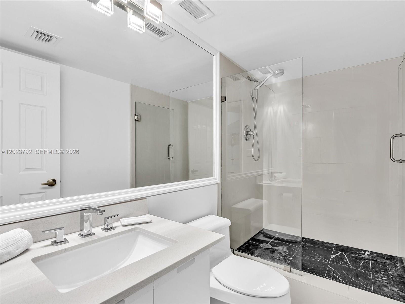 A modern bathroom features a white vanity, a glass-enclosed shower, and black marble flooring — 825 Brickell Bay Dr # 2048, Miami FL 33131, MIAMI, FL