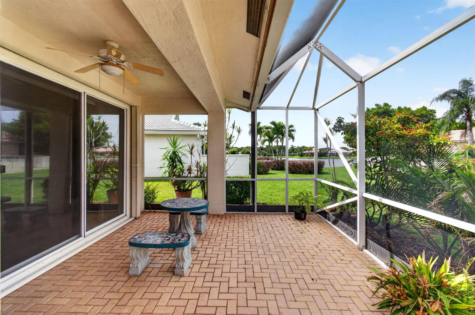A covered patio with brick pavers, a ceiling fan, and a screened-in view of landscaping — 2752 Clipper Circle, West Palm Beach FL 33411, WEST PALM BEACH, FL
