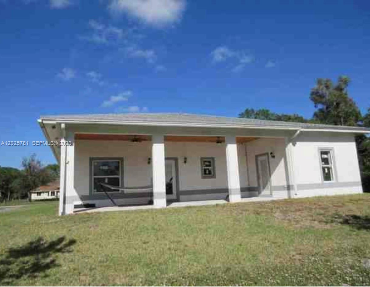 The exterior of a single-story house features a covered patio with columns and a lawn — LOXAHATCHEE, FL