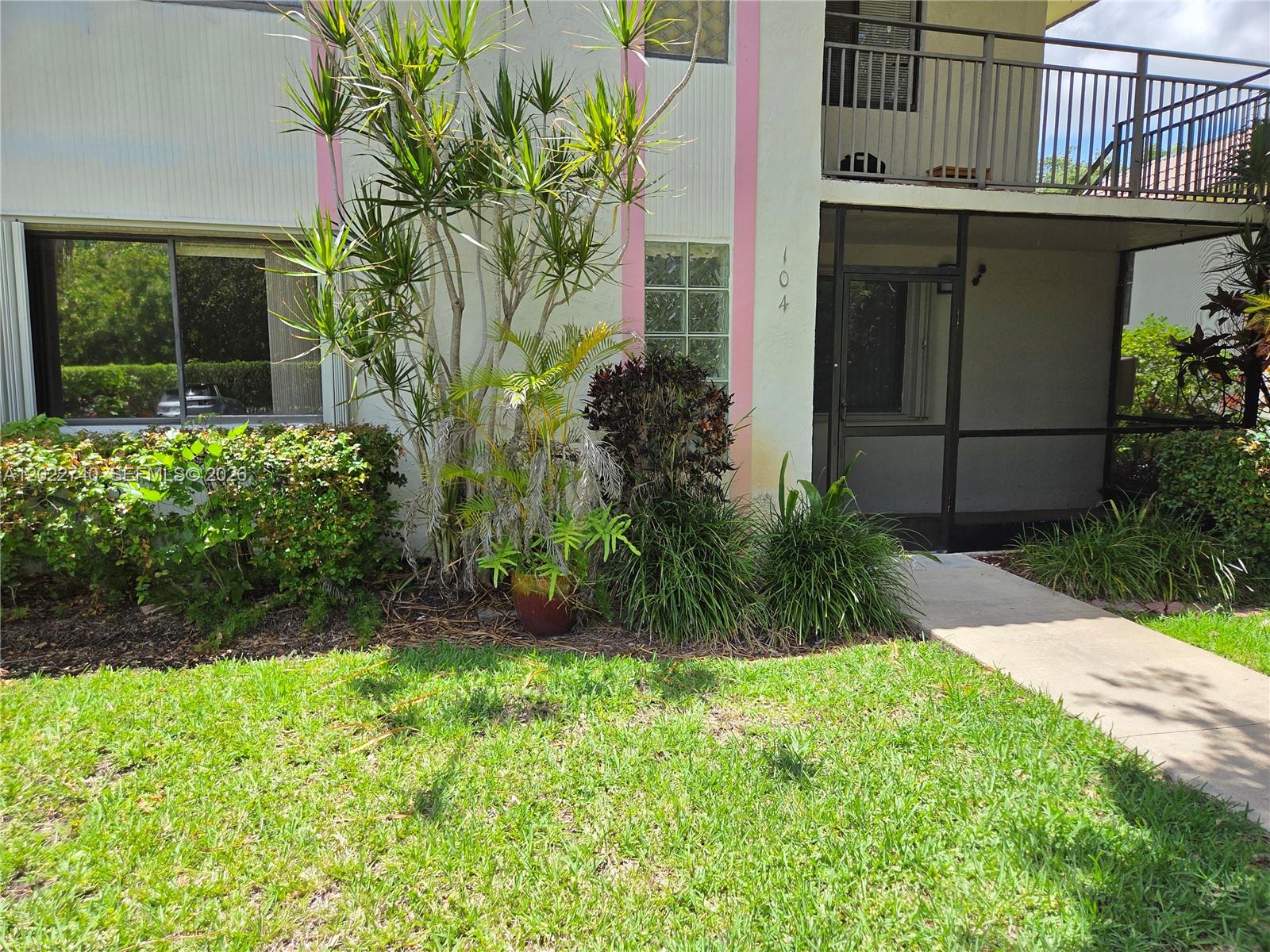 The exterior of a two-story building features a screened-in ground floor patio and landscaping — 413 Lakeview Dr # 104, Weston FL 33326, WESTON, FL