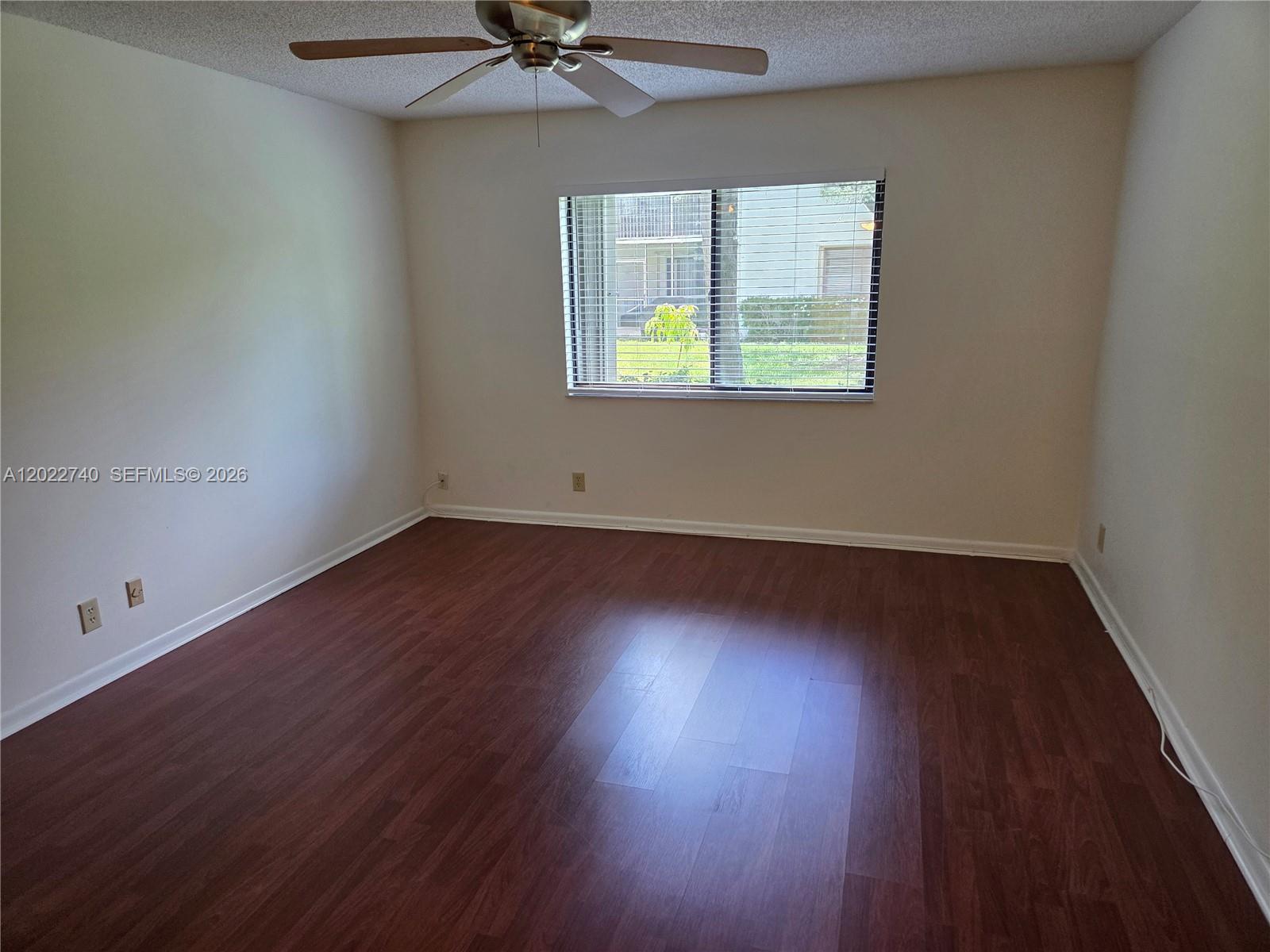 An empty bedroom features dark wood-look flooring, beige walls, and a ceiling fan — 413 Lakeview Dr # 104, Weston FL 33326, WESTON, FL