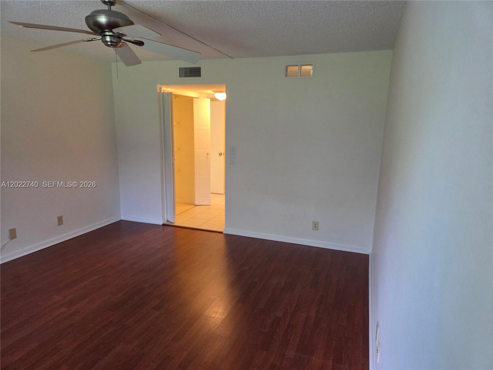An empty room features dark wood-look flooring, a ceiling fan, and an open doorway — 413 Lakeview Dr # 104, Weston FL 33326, WESTON, FL