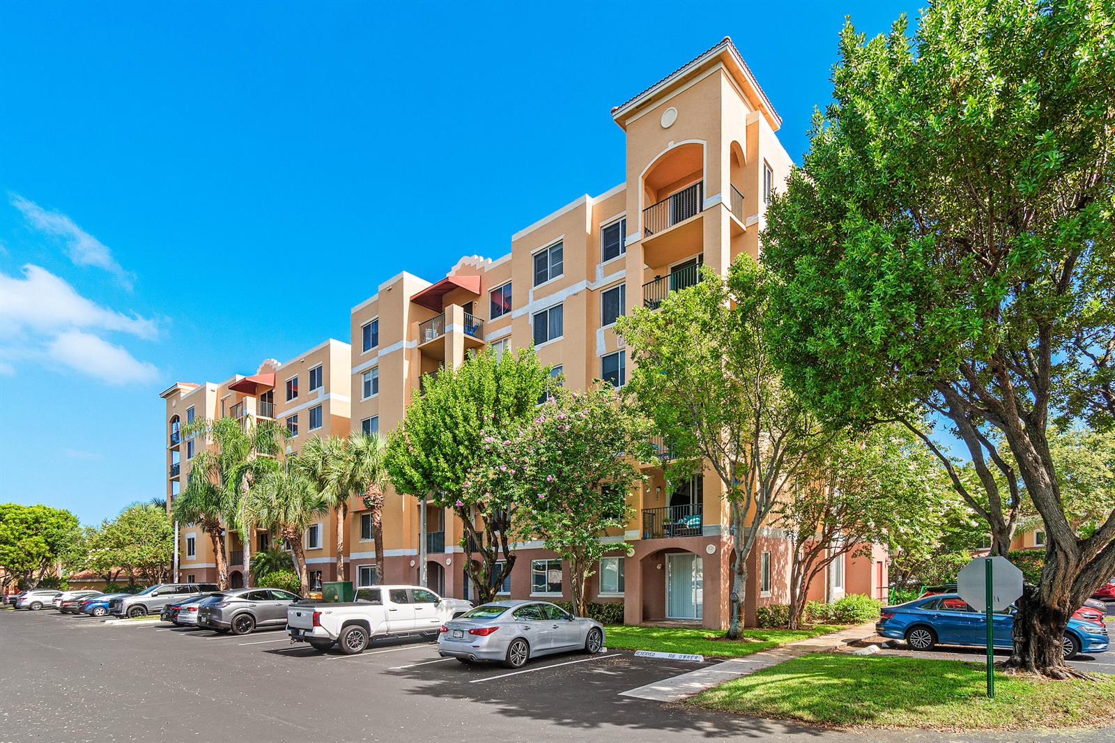 A multi-story apartment building with a tan stucco exterior stands beside a parking lot — 1000 Scotia Drive # 102, Hypoluxo FL 33462, HYPOLUXO, FL