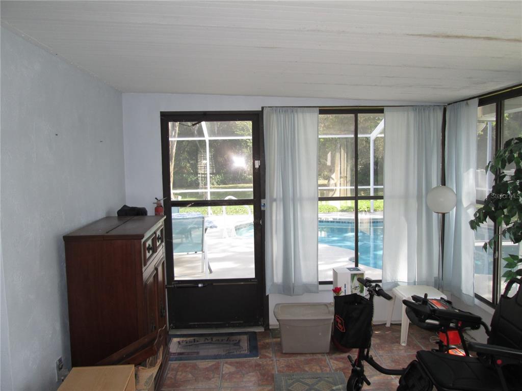 A sunroom with tile flooring, a screen door, and a view of a swimming pool — 155 VILLAGE LANE, DAYTONA BEACH, FL