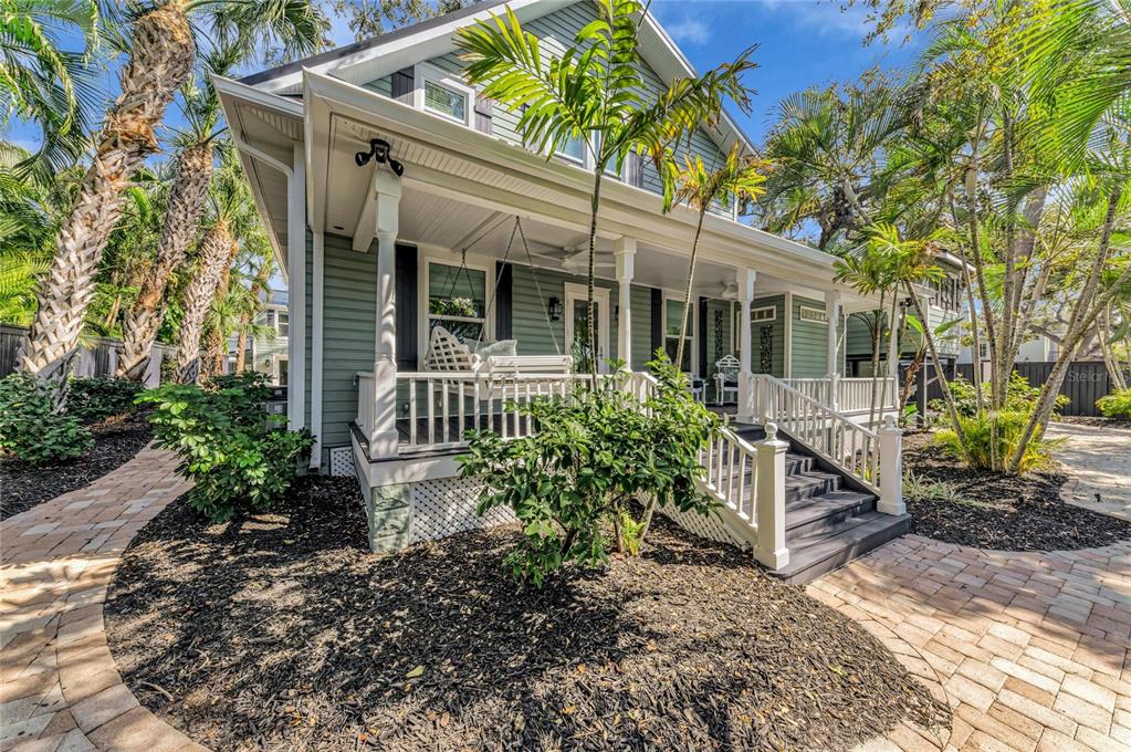 A light green house with a wrap-around porch, white railings, and a brick walkway — 1611 HYDE PARK STREET, SARASOTA, FL