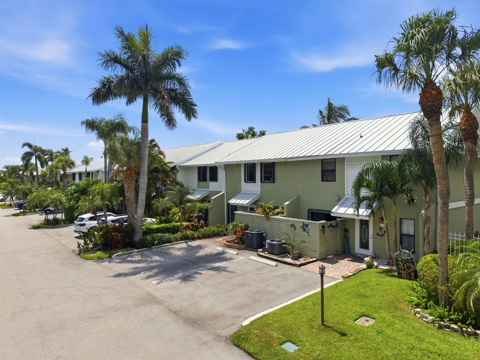 An exterior view of a green multi-unit residential building with palm trees and parking spaces — 626 Mariners Way, Boynton Beach FL 33435, BOYNTON BEACH, FL