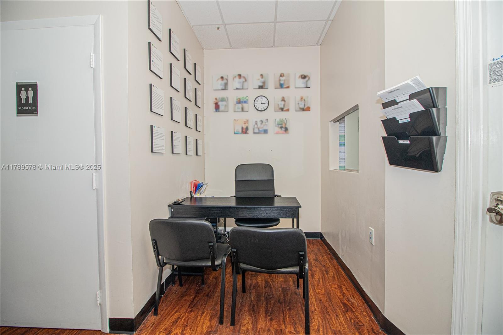 A small office features a black desk, three chairs, wall-mounted document holders, and wood-look flooring — 5580 W 16th Ave, Hialeah FL 33012, HIALEAH, FL