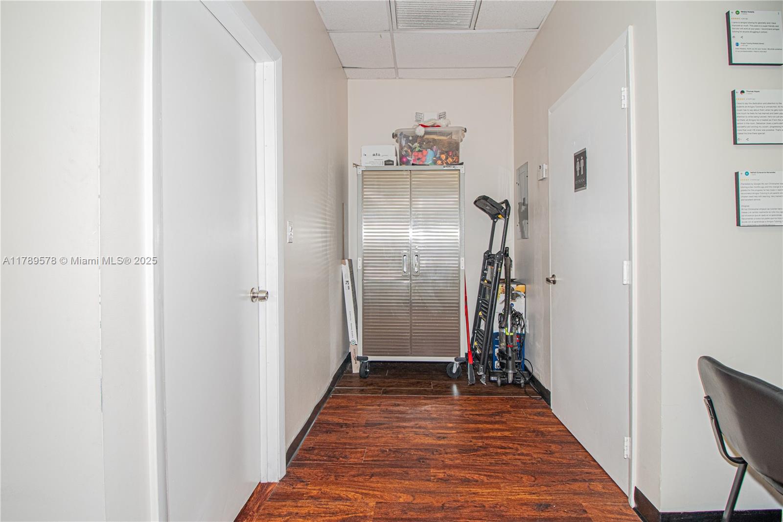 A hallway with wood-look flooring, a metal storage cabinet, and two white doors — 5580 W 16th Ave, Hialeah FL 33012, HIALEAH, FL
