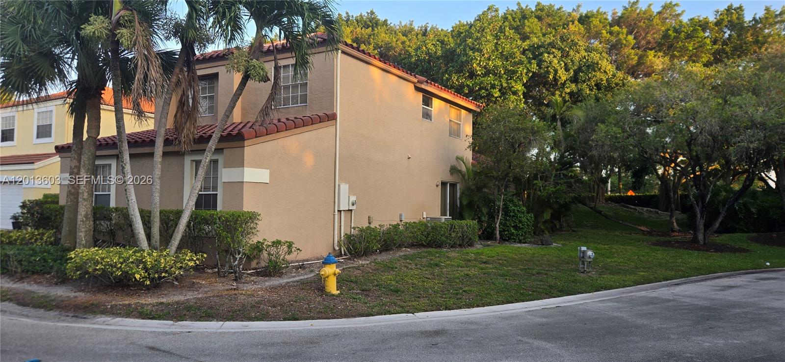 A two-story tan stucco house with a red tile roof sits beside a fire hydrant — 6470 NW 77th Pl, Parkland FL 33067, PARKLAND, FL
