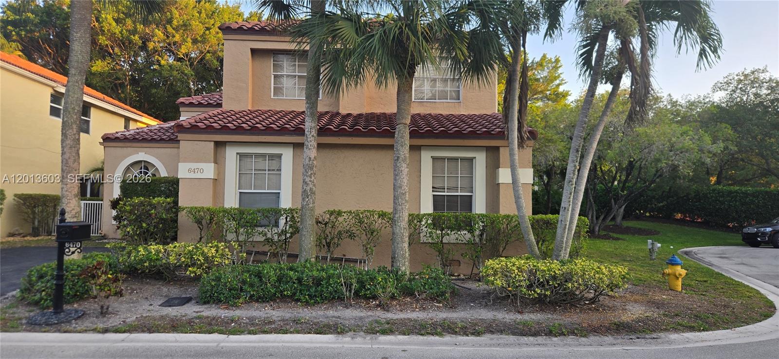 A two-story tan stucco house features a red tile roof and palm trees — 6470 NW 77th Pl, Parkland FL 33067, PARKLAND, FL