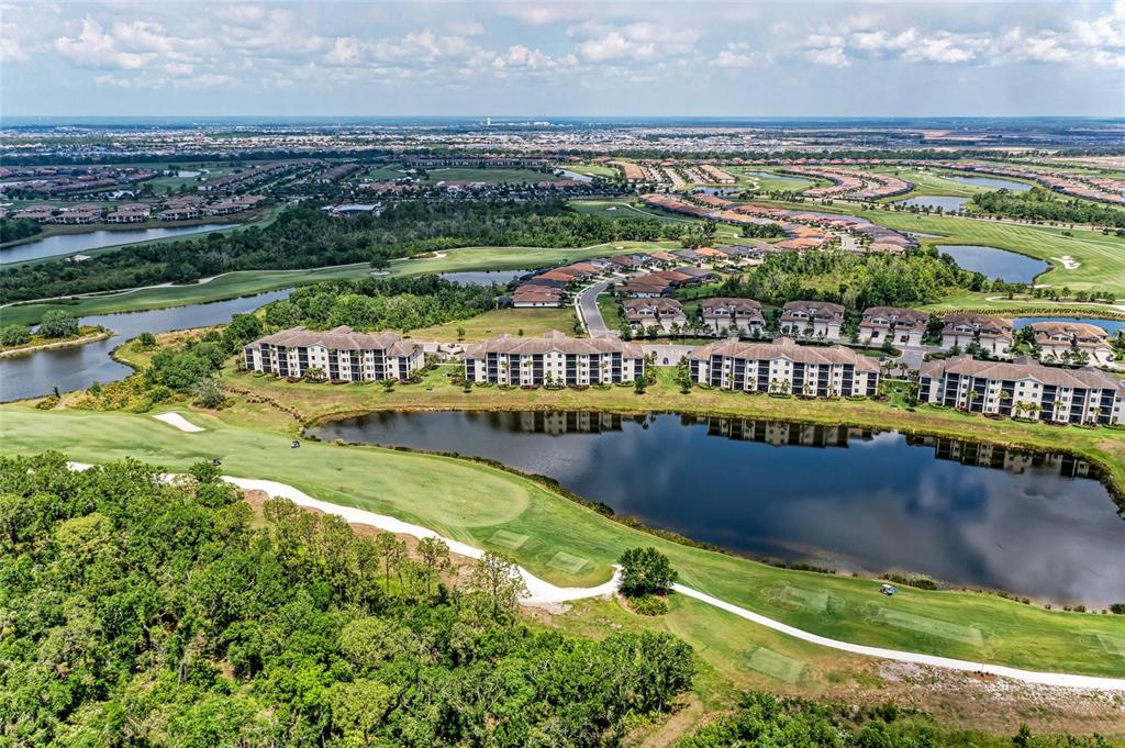 An aerial view shows multi-story residential buildings situated along a golf course and lake — 17520 GAWTHROP DRIVE UNIT 304, BRADENTON, FL