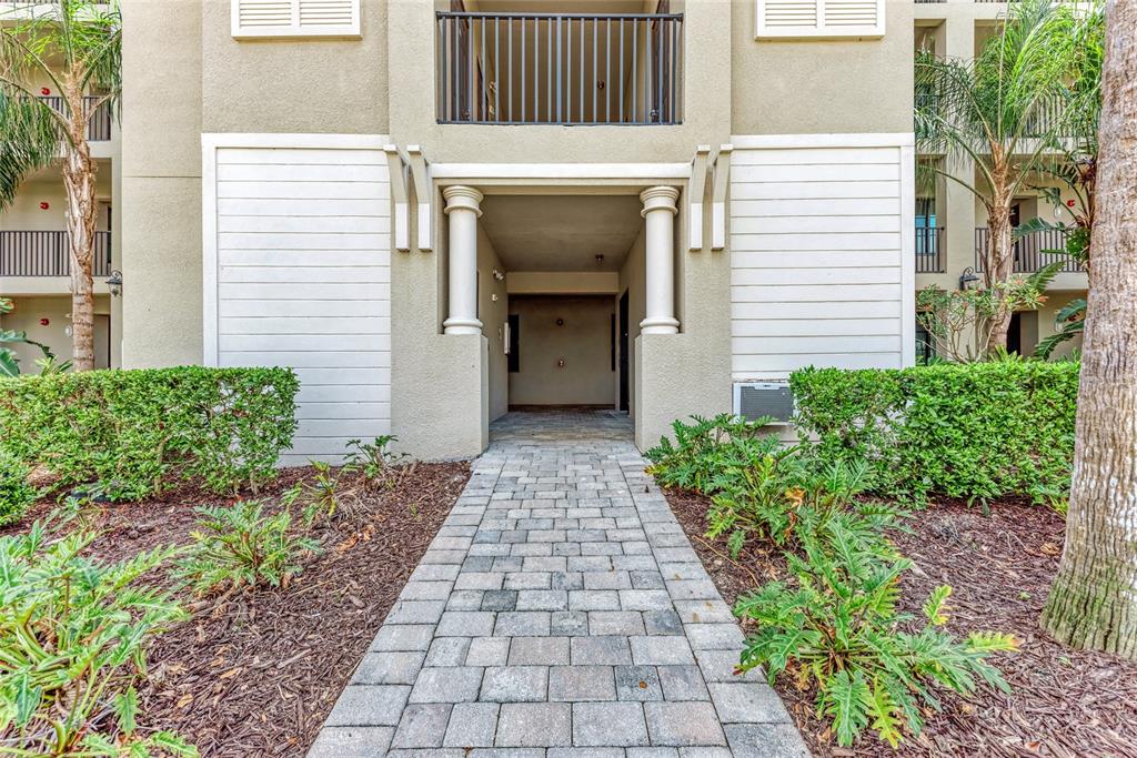 A paved walkway leads to the covered entrance of a multi-story apartment building — 17520 GAWTHROP DRIVE UNIT 304, BRADENTON, FL