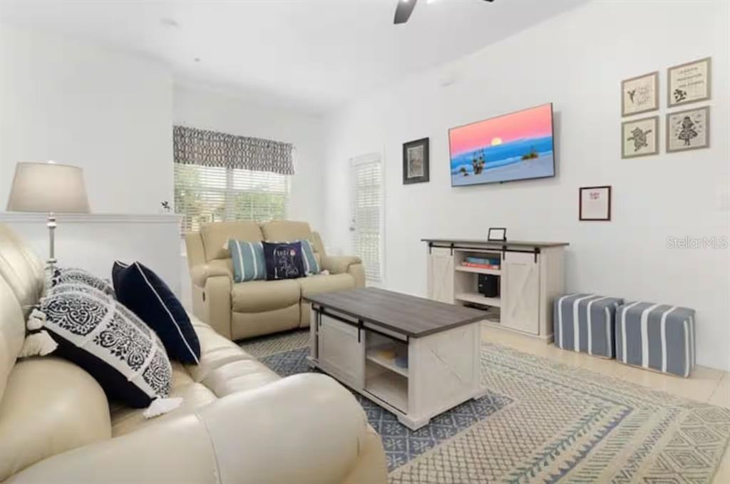 A living room features light-colored leather sofas, a wooden coffee table, and a wall-mounted television — 2888 OAKWATER DRIVE UNIT 2888, KISSIMMEE, FL