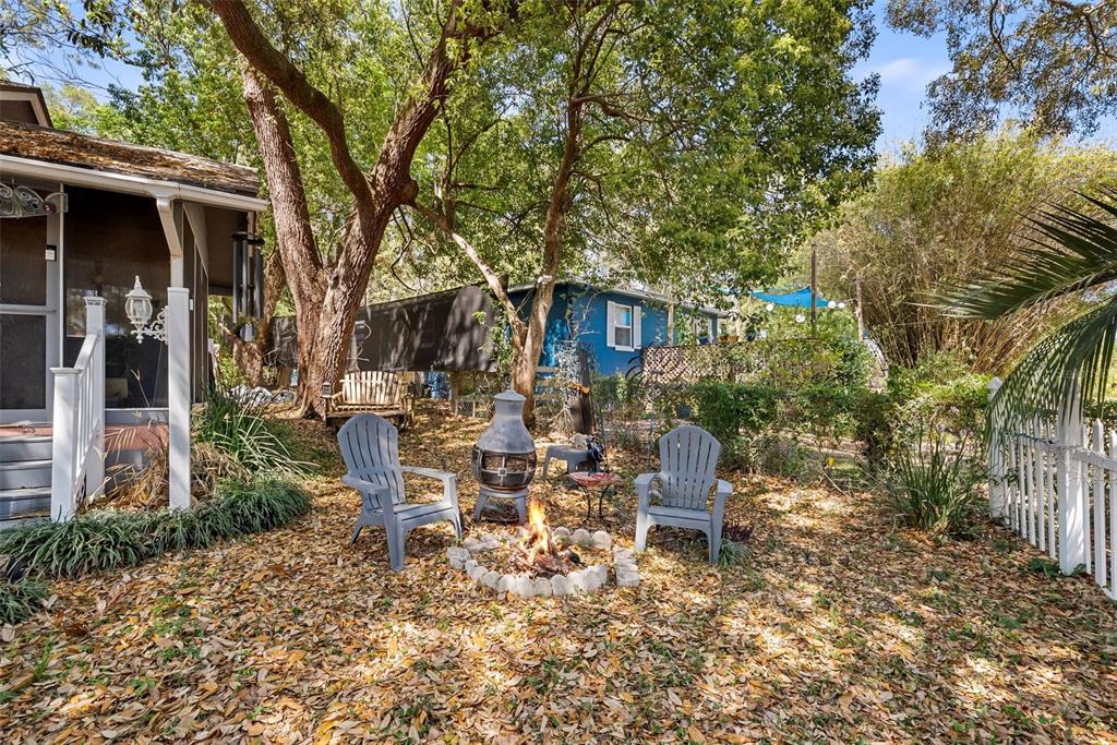 A backyard features a fire pit, two gray chairs, and a small patio area — 360 SE LAKEVIEW DRIVE, KEYSTONE HEIGHTS, FL