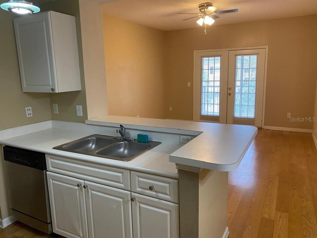 A kitchen with white cabinets, a double sink, and a breakfast bar overlooking a dining area — 14341 FREDRICKSBURG DR DRIVE UNIT 1007, ORLANDO, FL