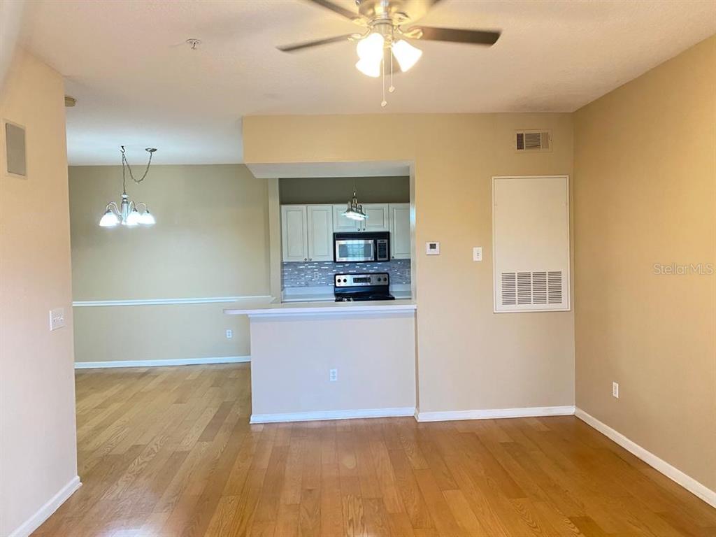 An open-concept living area features hardwood floors, a kitchen with white cabinets, and a ceiling fan — 14341 FREDRICKSBURG DR DRIVE UNIT 1007, ORLANDO, FL