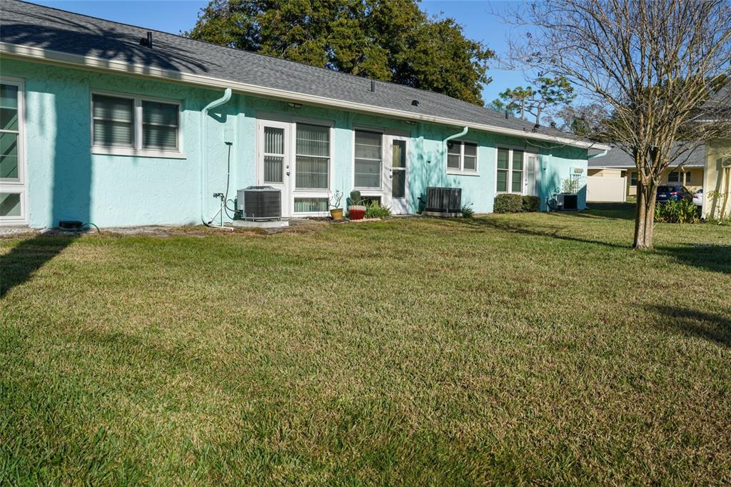 A light blue, single-story residential building with a gray shingled roof and a grassy yard — 2465 NORTHSIDE DRIVE UNIT 102, CLEARWATER, FL