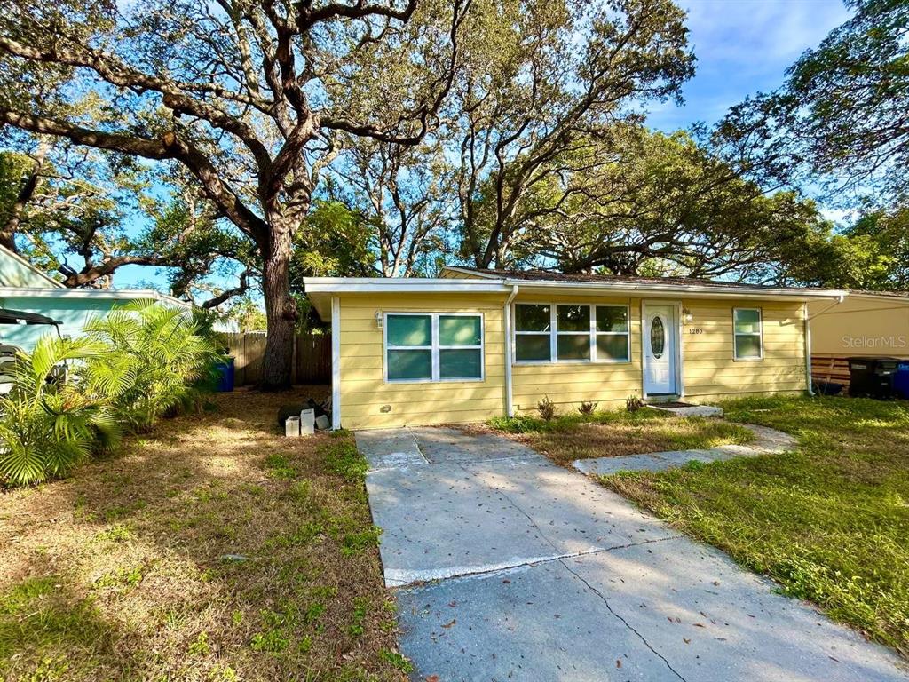 A single-story house with white horizontal siding, a blue trim, and a concrete driveway — 1280 BERTLAND WAY, CLEARWATER, FL