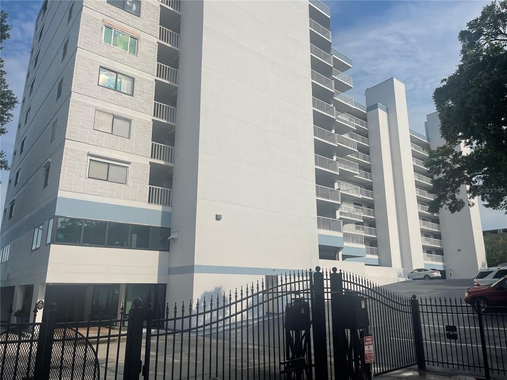 A multi-story apartment building with balconies and a gated entrance in the foreground — 2 ADALIA AVENUE UNIT 302, TAMPA, FL