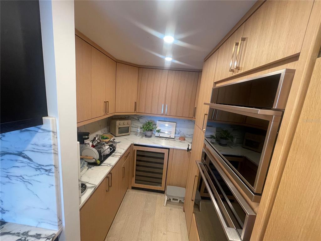 A galley kitchen features light wood cabinetry, marble countertops, and a built-in double oven — 2 ADALIA AVENUE UNIT 302, TAMPA, FL