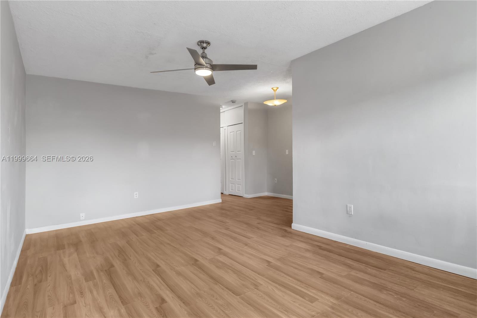 An empty room features light gray walls, wood-look flooring, and a ceiling fan — 8129 Abbott Ave # 10, Miami Beach FL 33141, MIAMI BEACH, FL