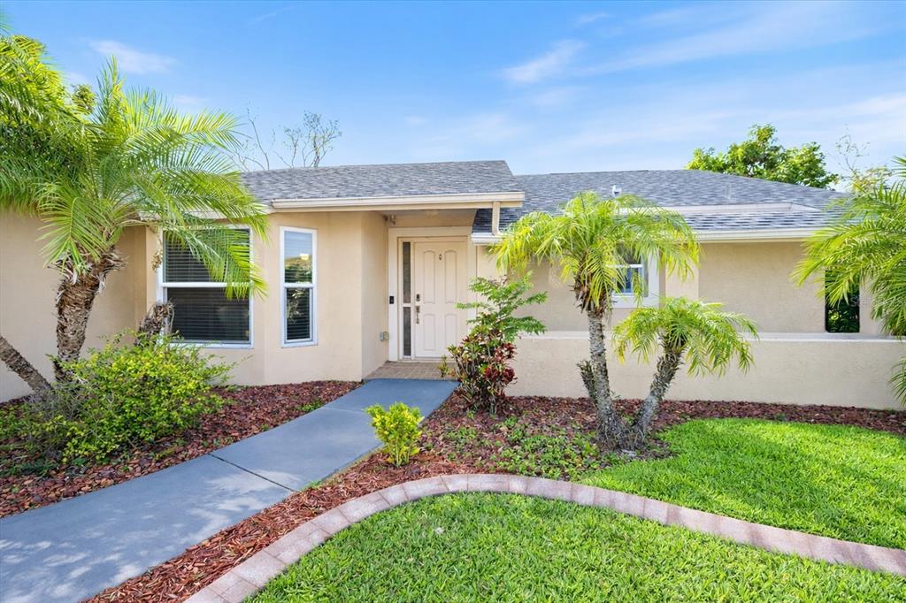 A single-story house with a beige stucco exterior, palm trees, and a concrete walkway — 1627 DEL MONTE COURT, VENICE, FL