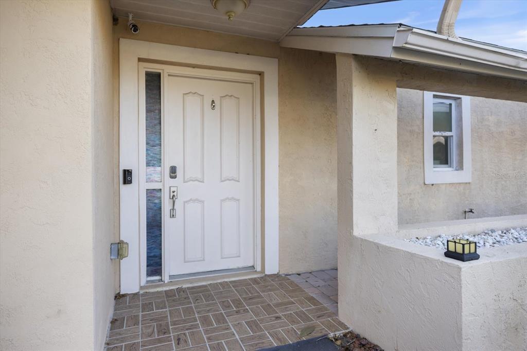 The exterior view shows a white front door with a sidelight and tiled porch — 1627 DEL MONTE COURT, VENICE, FL