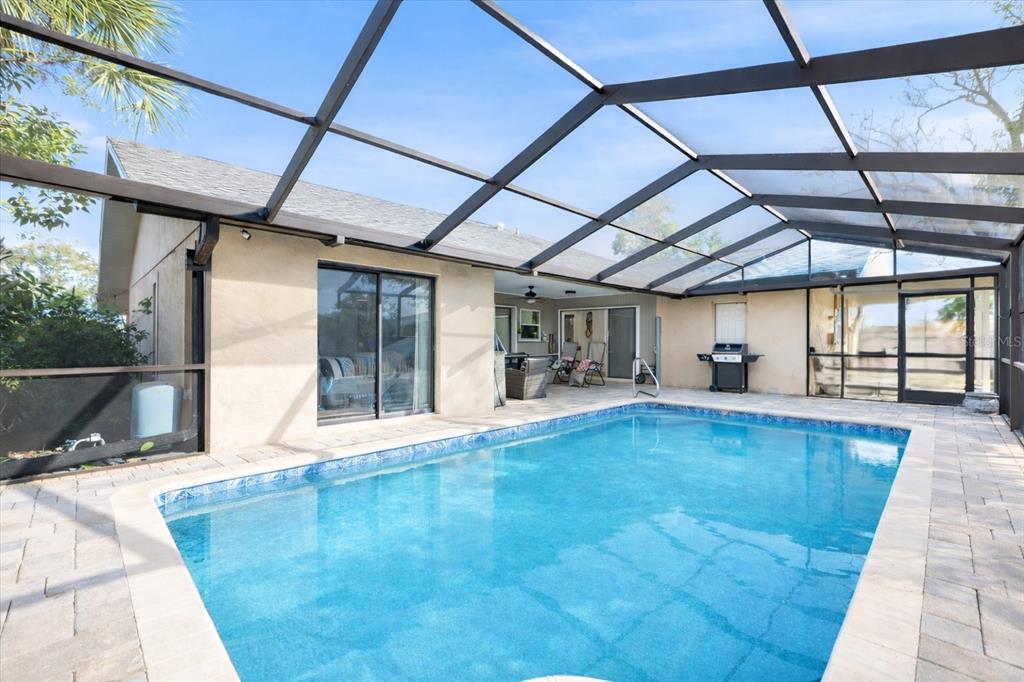 A swimming pool with a paved deck enclosed by a screened lanai attached to a house — 1627 DEL MONTE COURT, VENICE, FL