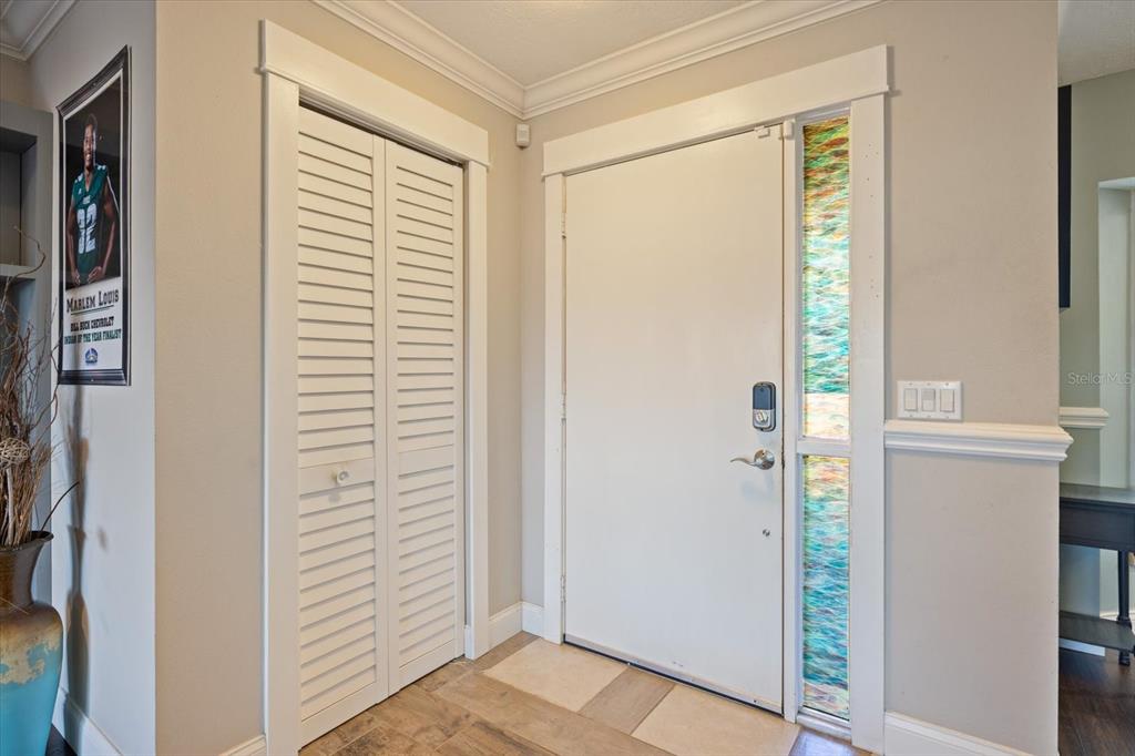 An entryway features a white louvered closet door, a front door with stained-glass sidelights, and flooring — 1627 DEL MONTE COURT, VENICE, FL