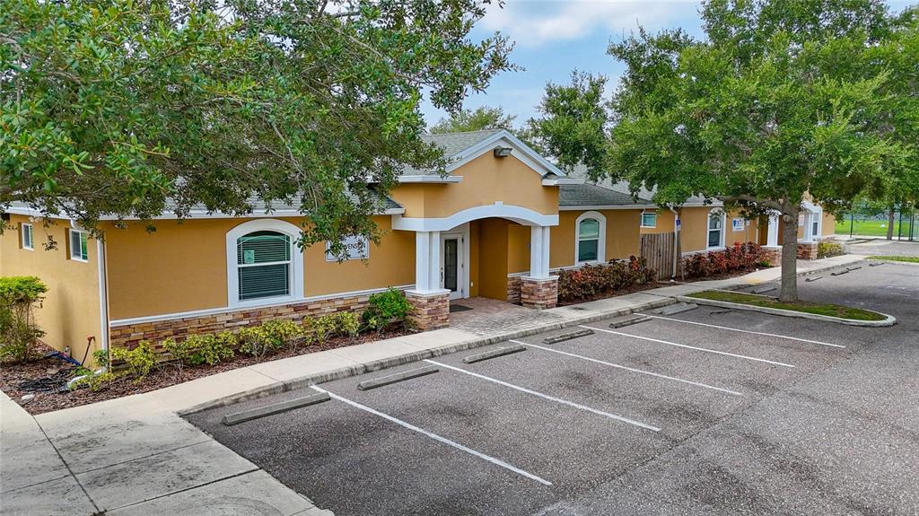 An exterior view of a single-story commercial building with a tan stucco facade and parking — 7318 W COMANCHE AVENUE, TAMPA, FL