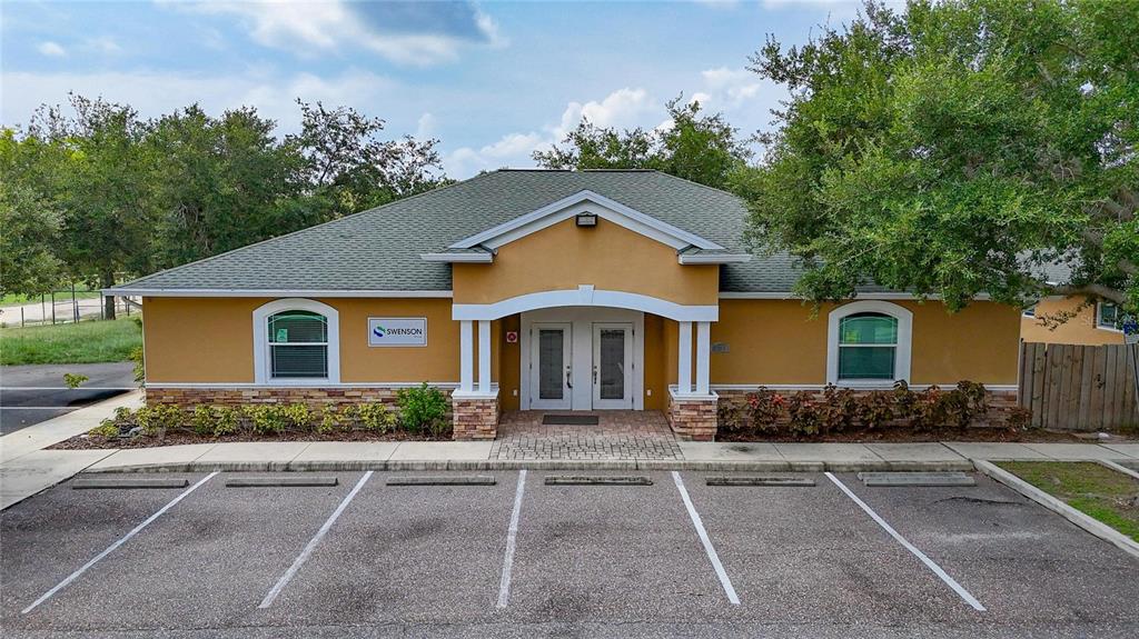 A single-story commercial building with a tan stucco exterior, stone accents, and a parking lot — 7318 W COMANCHE AVENUE, TAMPA, FL