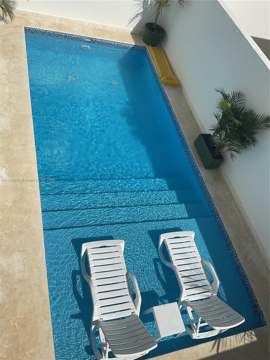 A rectangular swimming pool features a shallow tanning ledge with two lounge chairs and steps — 3 SW Calle el sol, Re, Re