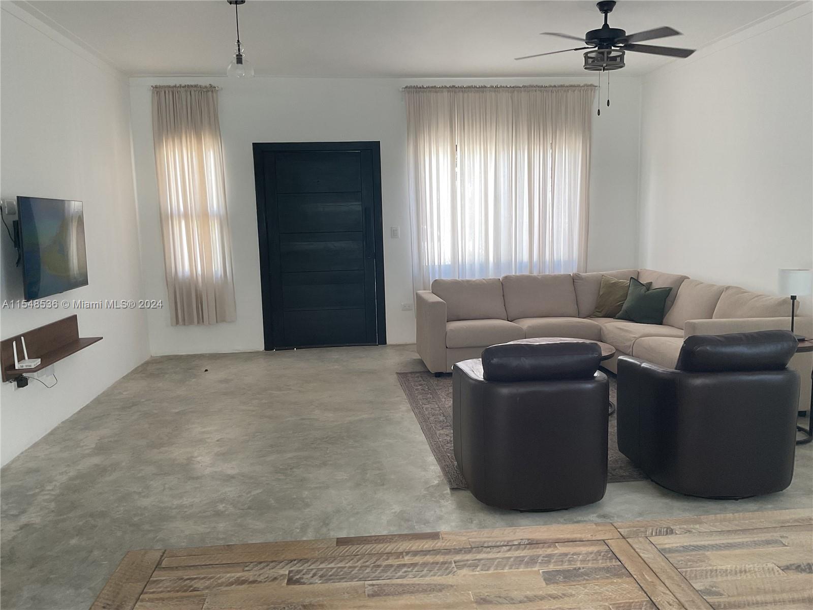 A living room features a concrete floor, a sectional sofa, two armchairs, and a television — 3 SW Calle el sol, Re, Re